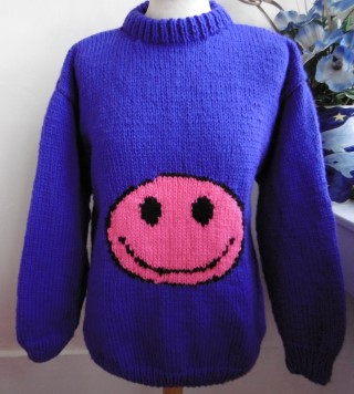hand knitted chunky sweater with a purple smiley face on the front